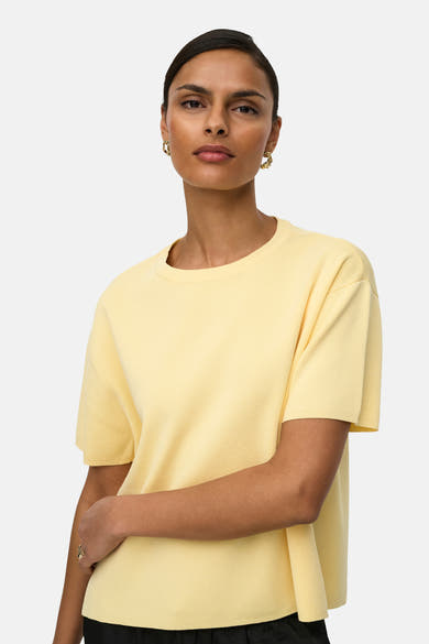 Pull jaune à col rond de JDY, en maille texturée, porté avec des boucles d'oreilles dorées.