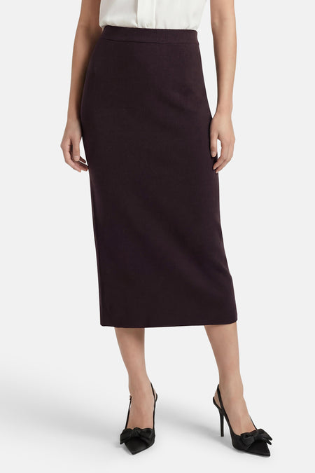 Jupe 3/4 brun de JDY en maille texturée, portée avec une blouse blanche et des escarpins noirs à nœud.