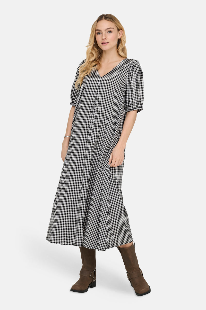 Robe à carreaux multicolore de JDY, avec une coupe évasée et des manches courtes bouffantes, portée avec des bottes marron.
