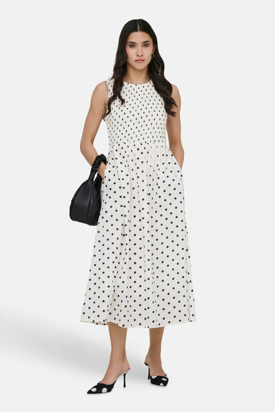 Robe blanche à pois noirs de JDY, portée avec un sac à main noir et des escarpins à pois assortis.