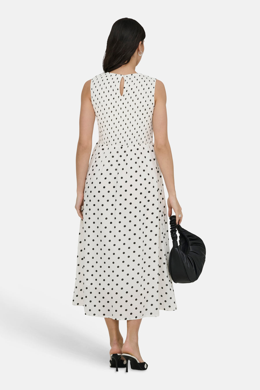 Witte jurk met stippen van JDY, van achteren gezien, met smockdetail en zwarte tas.