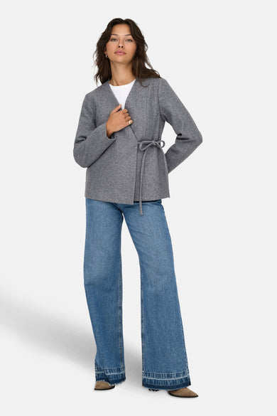 Veste courte gris de ONLY®, portée avec un t-shirt blanc et un jean ample.
