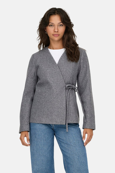 Veste courte grise de ONLY, avec une ceinture nouée et portée sur un t-shirt blanc et un jean bleu.
