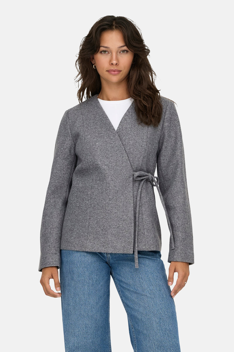 Veste courte grise de ONLY, avec une ceinture nouée et portée sur un t-shirt blanc et un jean bleu.
