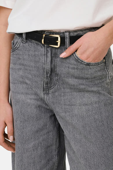 Jean gris moyen en denim par JDY, avec ceinture noire et boucle dorée, main dans la poche.