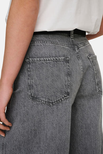 Jean en denim gris moyen de JDY, montrant la poche arrière, porté avec un t-shirt blanc.