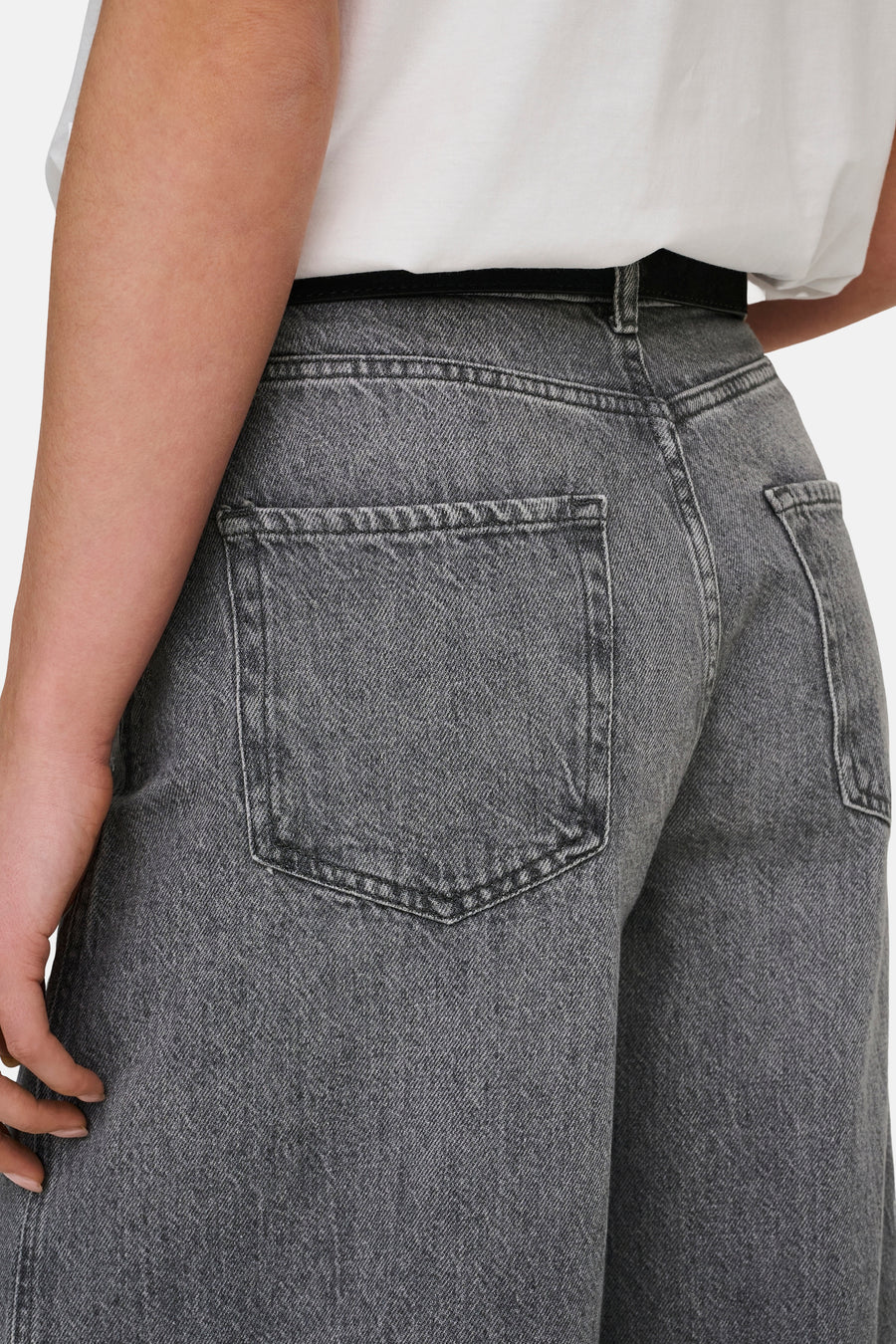 Jean en denim gris moyen de JDY, montrant la poche arrière, porté avec un t-shirt blanc.