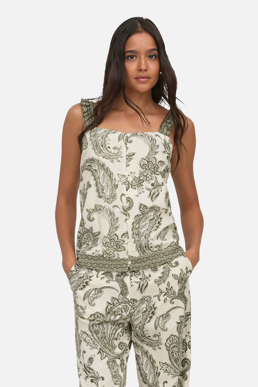 Ivy green sleeveless blouse with floral paisley print, ruffled straps, and front buttons, shown on model in front view.