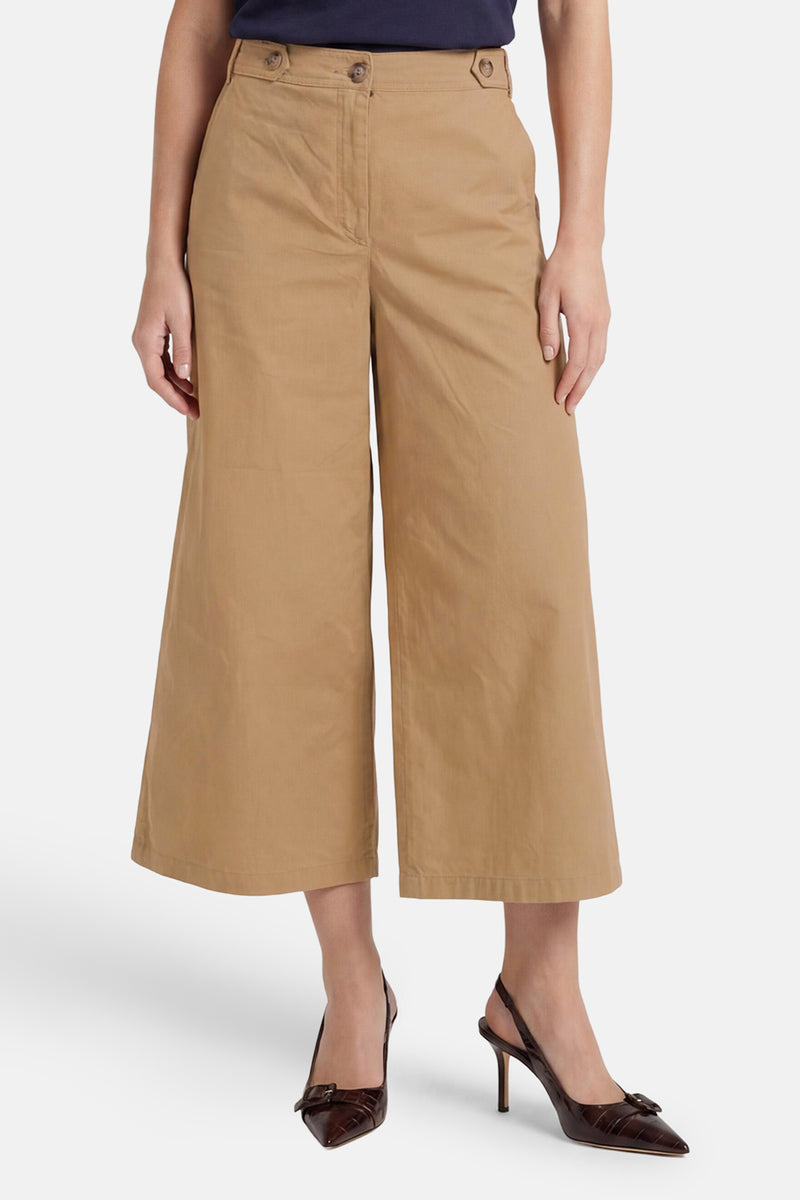Beige wide-leg cropped pants with front buttons and clean hem, worn with dark top and brown heels, front view