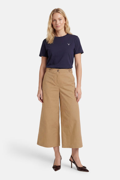 Beige wide-leg cropped pants with front pockets and button waist, worn with navy t-shirt and brown heels, full-length front view