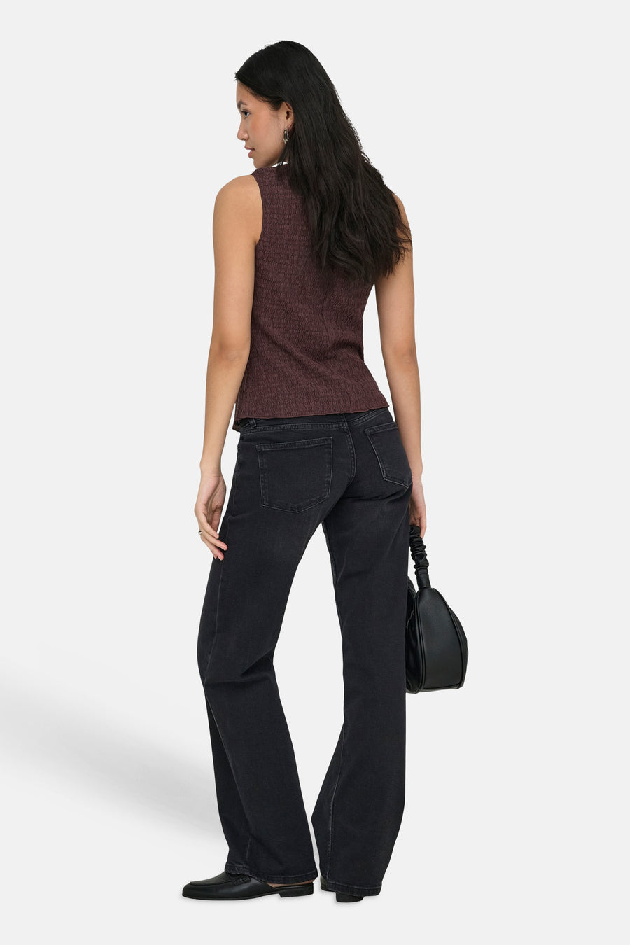 Bruin ONLY® gilet met wafeltextuur, gedragen met een zwarte uitlopende jeans en loafers.