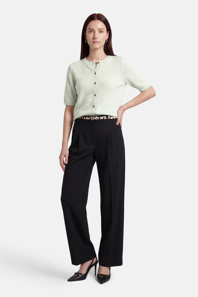 Pull vert de JDY porté avec un pantalon noir large et des escarpins noirs à talons.
