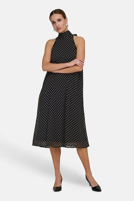 Robe noire de JDY à pois blancs, coupe mi-longue évasée et col montant noué.