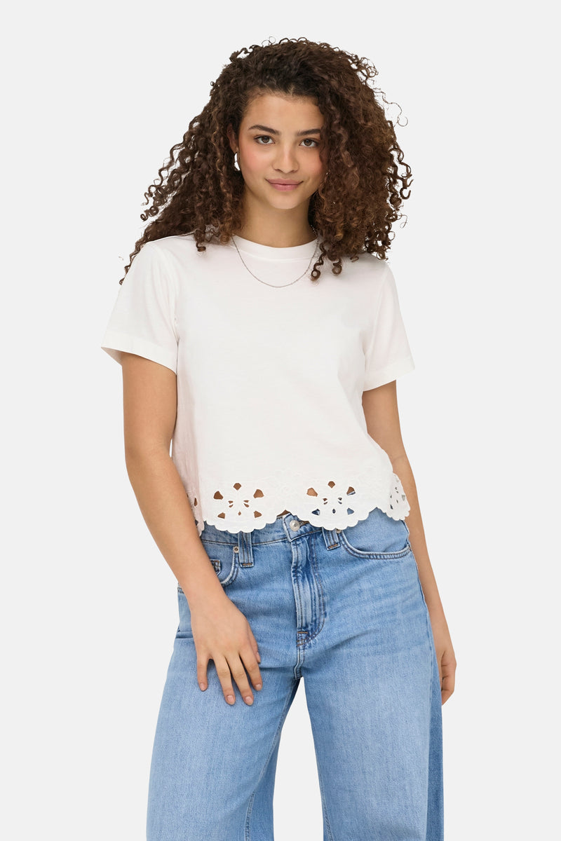 T-shirt blanc à manches courtes de ONLY® avec bordure festonnée à découpes, porté avec un jean clair.