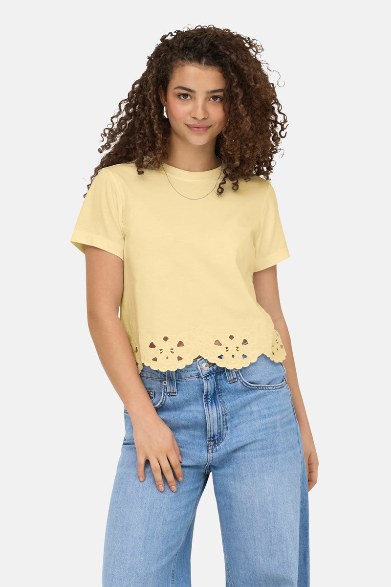 T-shirt jaune de ONLY avec ourlet festonné à découpes, porté avec un jean et un collier fin.