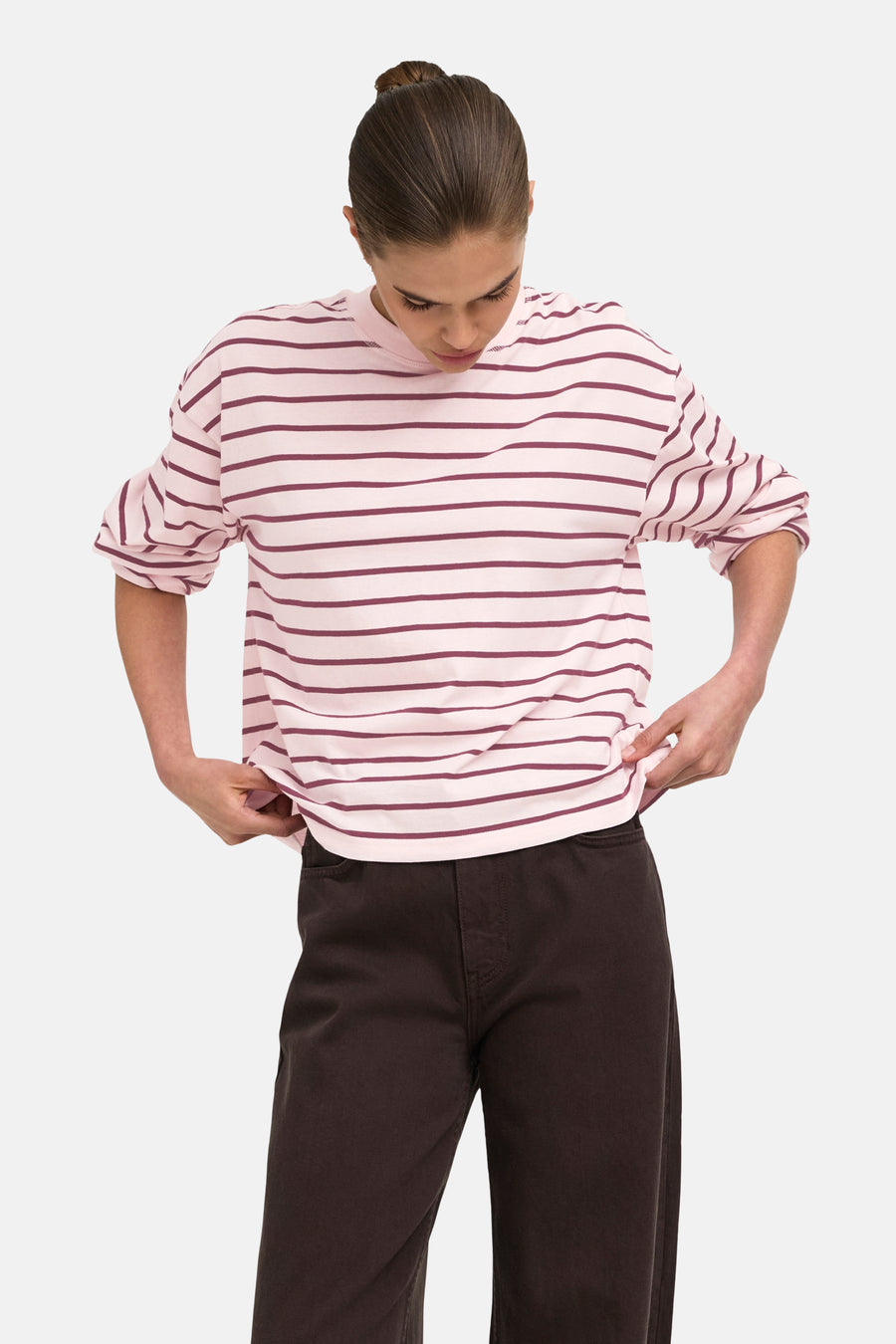 Pale lilac long-sleeve t-shirt with horizontal stripes, worn by model with sleeves rolled, paired with dark wide-leg pants.