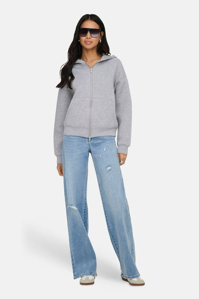 Gilet gris zippé de ONLY, porté avec un jean ample bleu clair et des lunettes de soleil noires.
