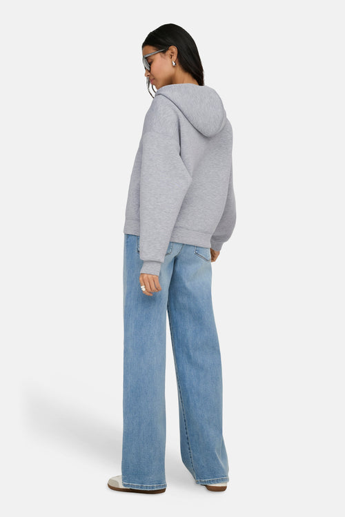Gilet gris ONLY®, porté avec un jean ample bleu et des chaussures décontractées blanches, vue de dos.
