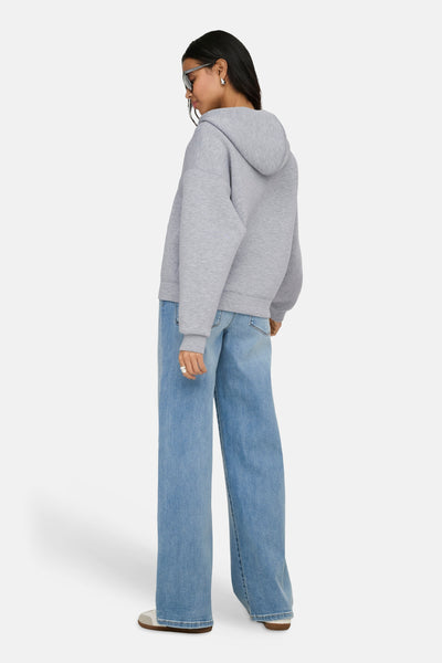 Gilet gris ONLY®, porté avec un jean ample bleu et des chaussures décontractées blanches, vue de dos.
