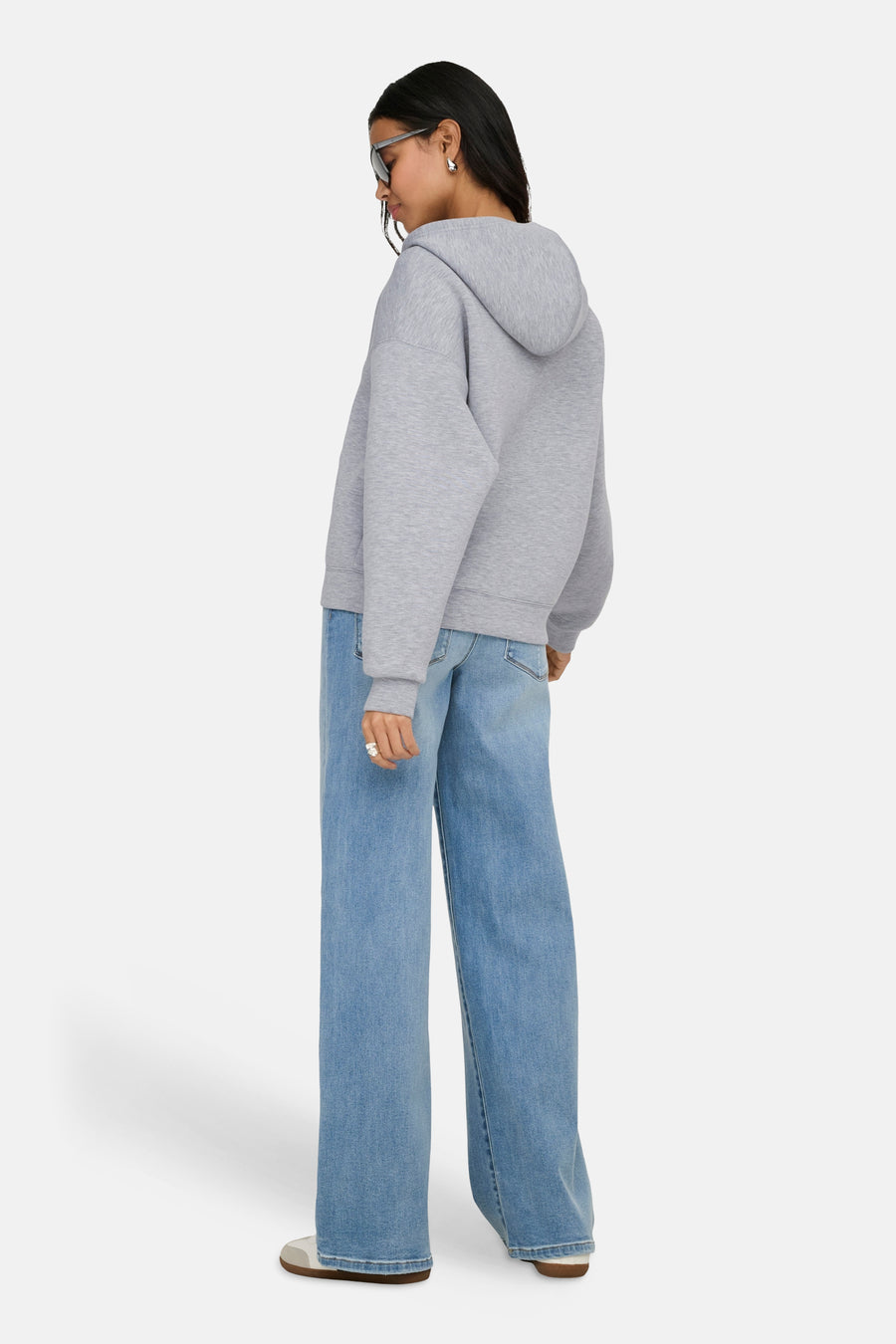 Gilet gris ONLY®, porté avec un jean ample bleu et des chaussures décontractées blanches, vue de dos.
