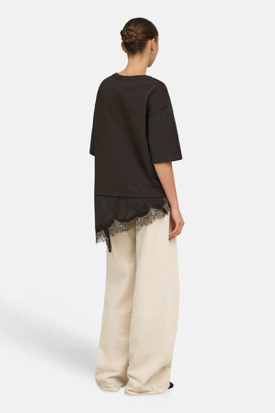Dark brown short-sleeve t-shirt with lace hem detail, back view, worn with cream wide-leg pants
