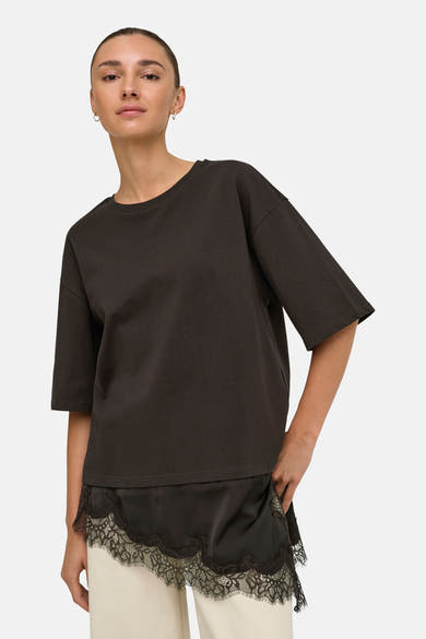 Dark brown short-sleeve t-shirt with lace-trimmed hem, worn by model in front view, paired with cream pants.