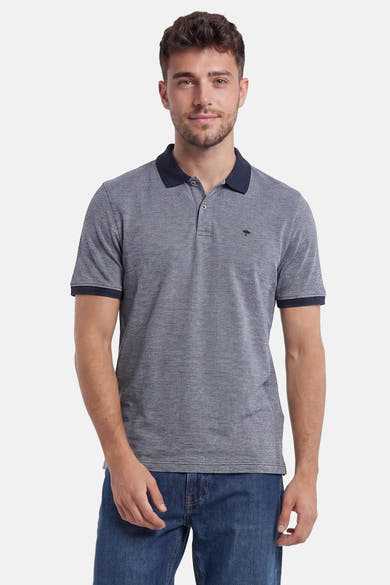 Polo bleu texturé de FYNCH-HATTON avec col et bordures marine, petit logo arbre, porté par un homme en jean.