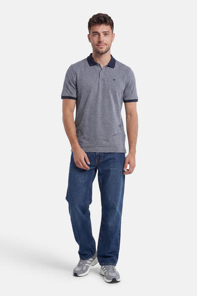 Polo bleu chiné de FYNCH-HATTON avec logo kangourou, col et bords de manches marine, porté avec un jean.