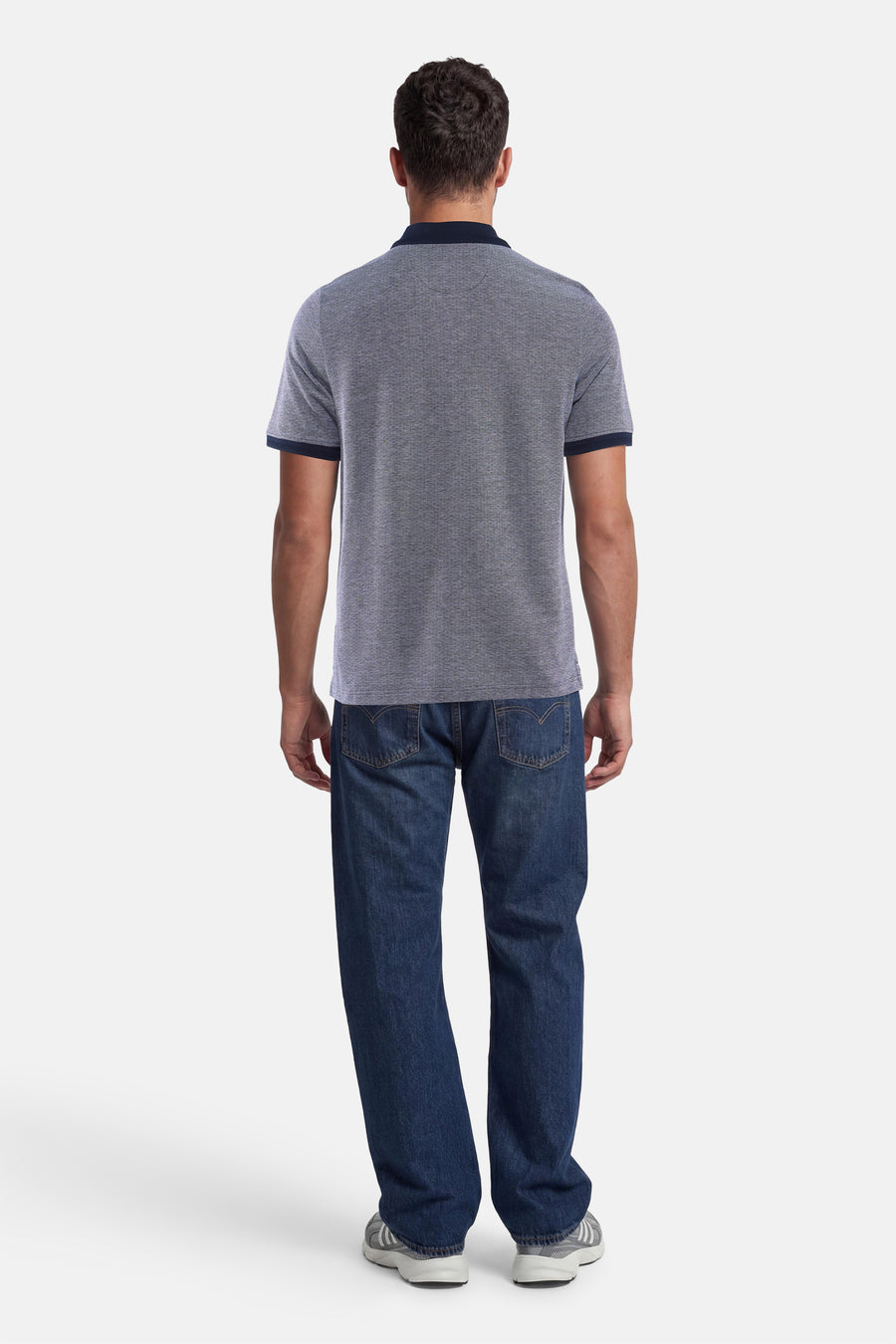 Polo bleu de FYNCH-HATTON à micro-motif, col et bordures des manches marine, vue de dos sur un homme en jean.