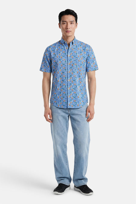 Chemise à manches courtes multicolore de FYNCH-HATTON, à motif floral bleu, orange et vert, portée avec un jean et des baskets.