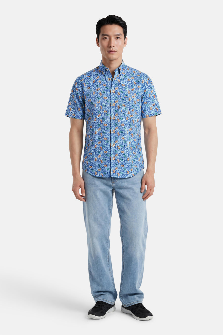 Chemise à manches courtes multicolore de FYNCH-HATTON, à motif floral bleu, orange et vert, portée avec un jean et des baskets.