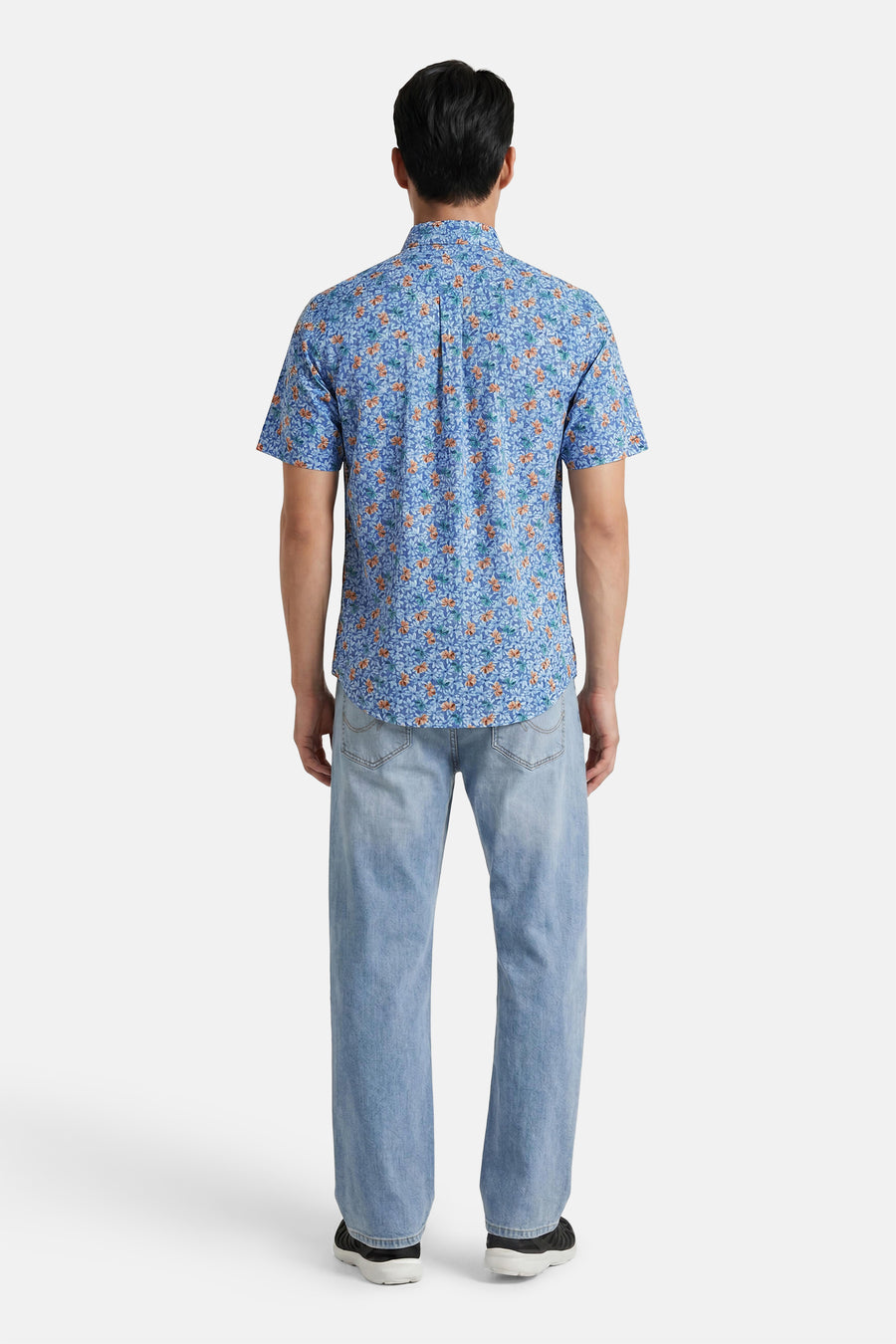 Chemise multicolore de FYNCH-HATTON à manches courtes, motif floral bleu et orange, portée avec un jean clair et des baskets.