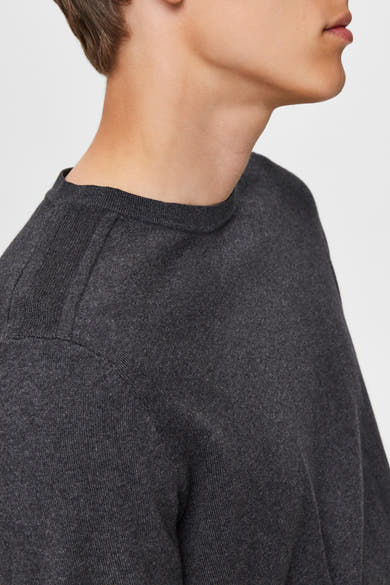 Pull gris en maille par SELECTED, détail de couture à l'épaule, porté par un homme, en vue rapprochée.
