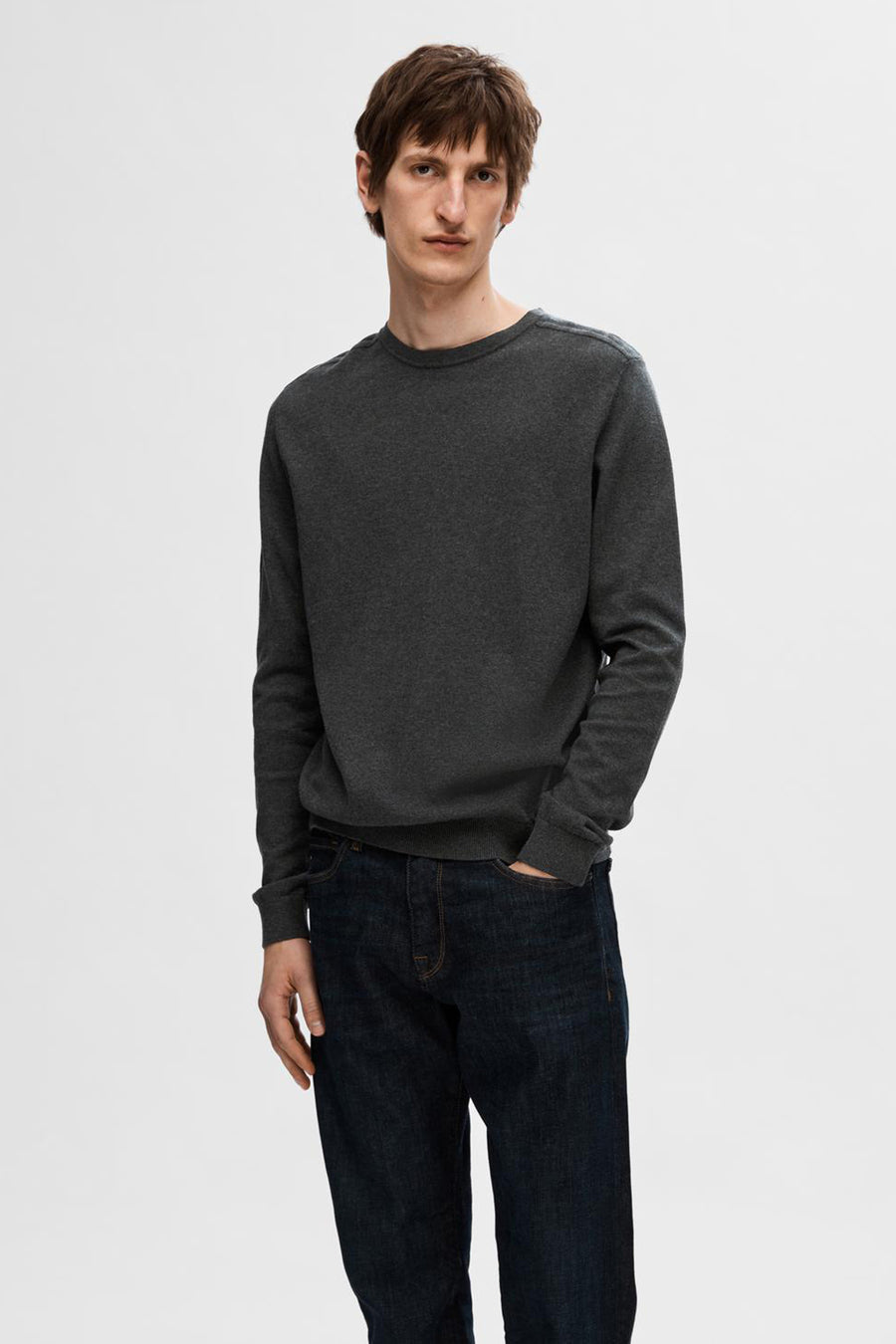 Pull gris à col rond de SELECTED, porté avec un jean sombre.