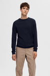 Pull bleu à col rond de SELECTED, porté avec un pantalon chino beige.