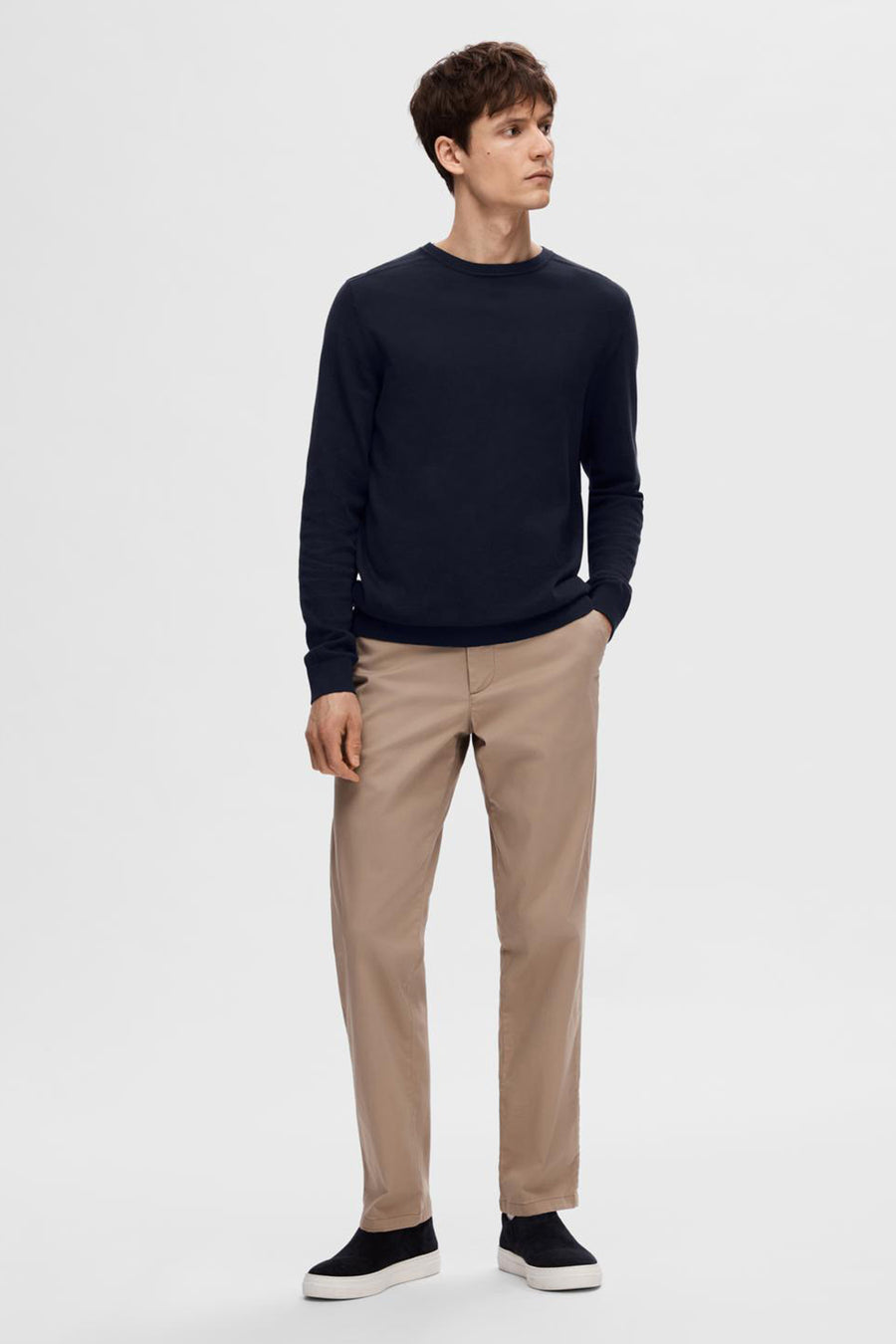Pull bleu de SELECTED, porté avec un pantalon chino beige et des chaussures décontractées noires.