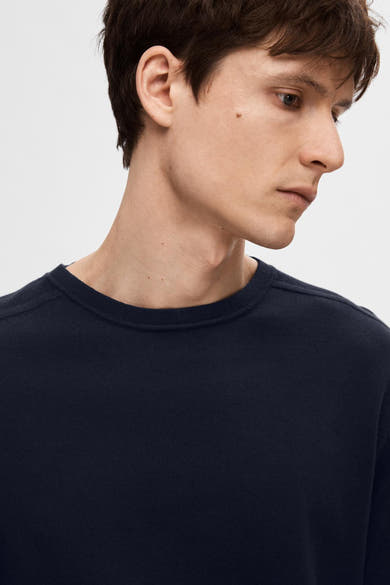 Pull bleu marine SELECTED avec une texture tricotée fine, porté avec un col rond.