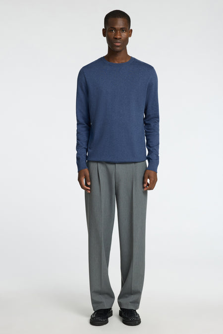 Pull à col rond bleu de SELECTED, porté avec un pantalon gris plissé et des mocassins noirs.