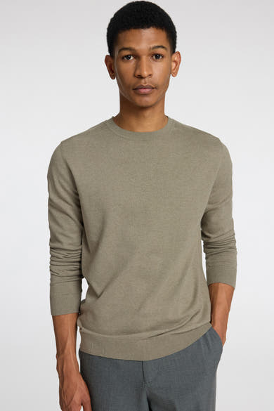 Pull vert à col rond de SELECTED, porté avec un pantalon gris.
