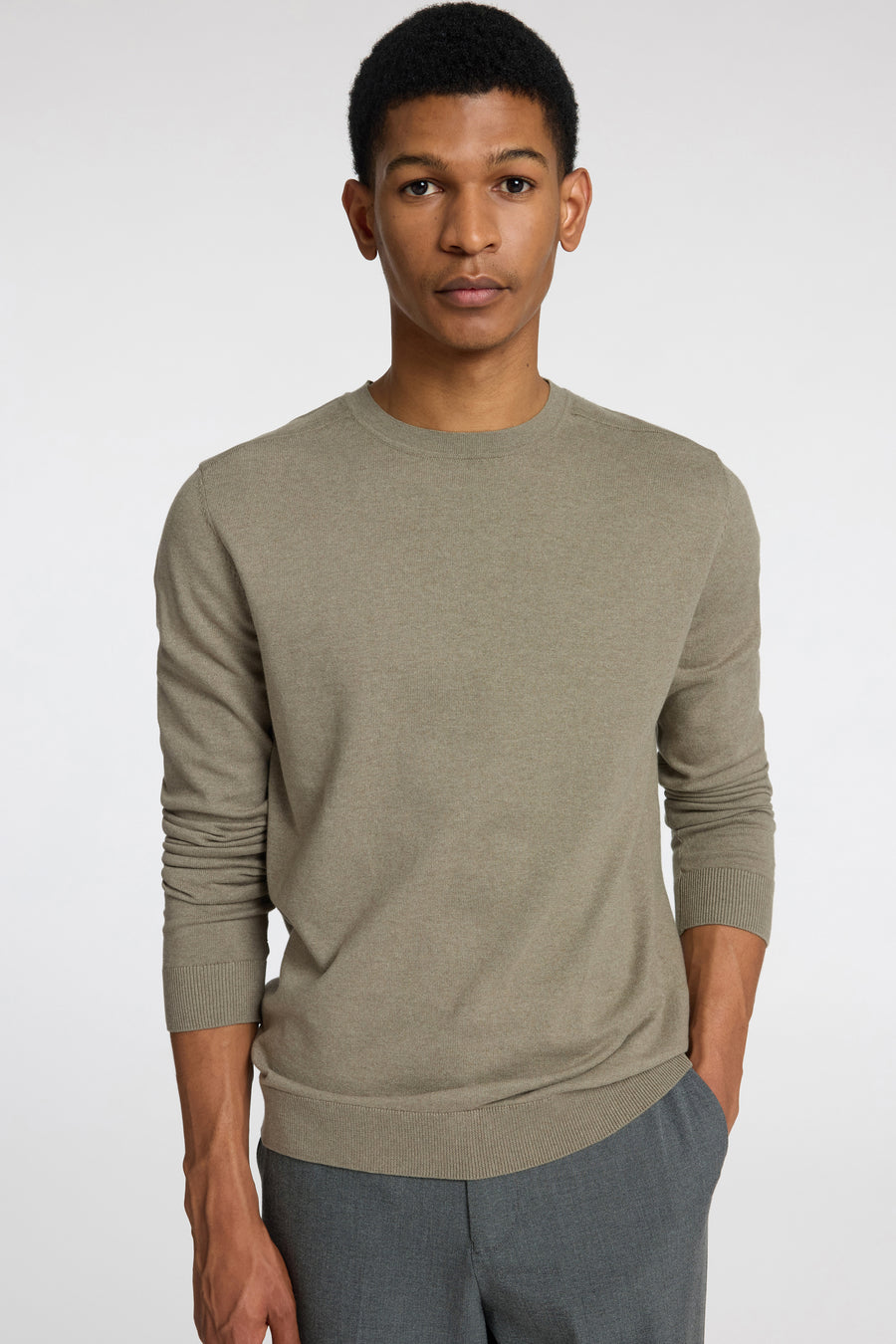 Pull vert à col rond de SELECTED, porté avec un pantalon gris.
