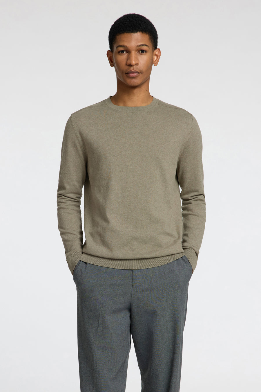 Pull vert de SELECTED, avec des manches longues et un col rond, porté avec un pantalon gris.
