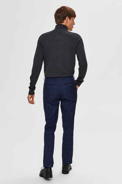 Grijze coltrui van SELECTED, gedragen met een marineblauwe geruite broek en zwarte schoenen.