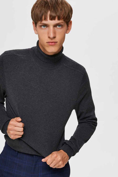 Pull col montant gris de SELECTED, porté avec un pantalon à carreaux bleus.