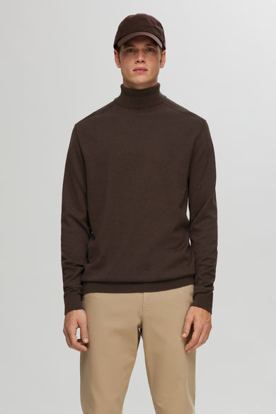 Pull à col roulé marron SELECTED porté avec un pantalon beige et une casquette.
