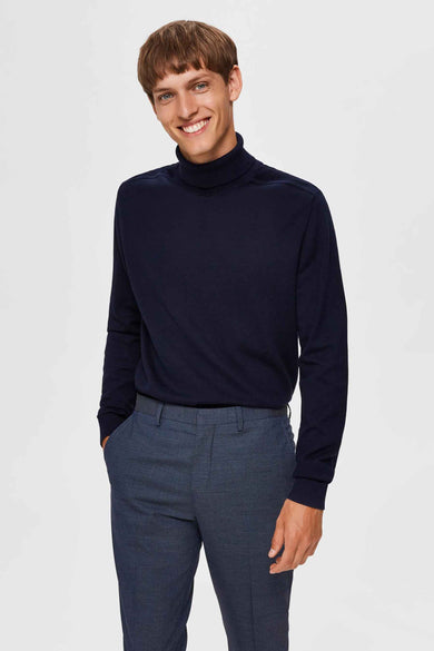 Blauwe coltrui van SELECTED, gedragen met een grijsblauwe nette broek en bruine leren schoenen.