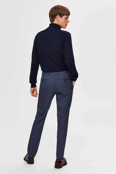 Pull col montant bleu de SELECTED, porté avec un pantalon de ville bleu chiné et des chaussures en cuir marron.