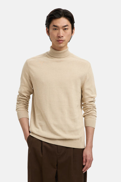 Beige coltrui van SELECTED, gedragen met een bruine pantalon met plooien.