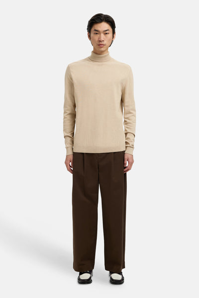 Beige coltrui van SELECTED, gedragen met een losse bruine broek en tweekleurige loafers.