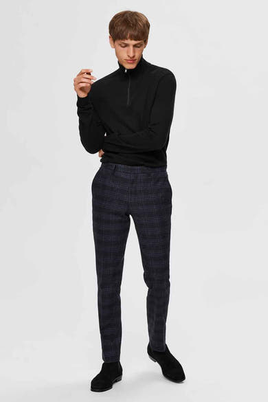 Pull noir de SELECTED, porté avec un pantalon à carreaux et des bottines noires.