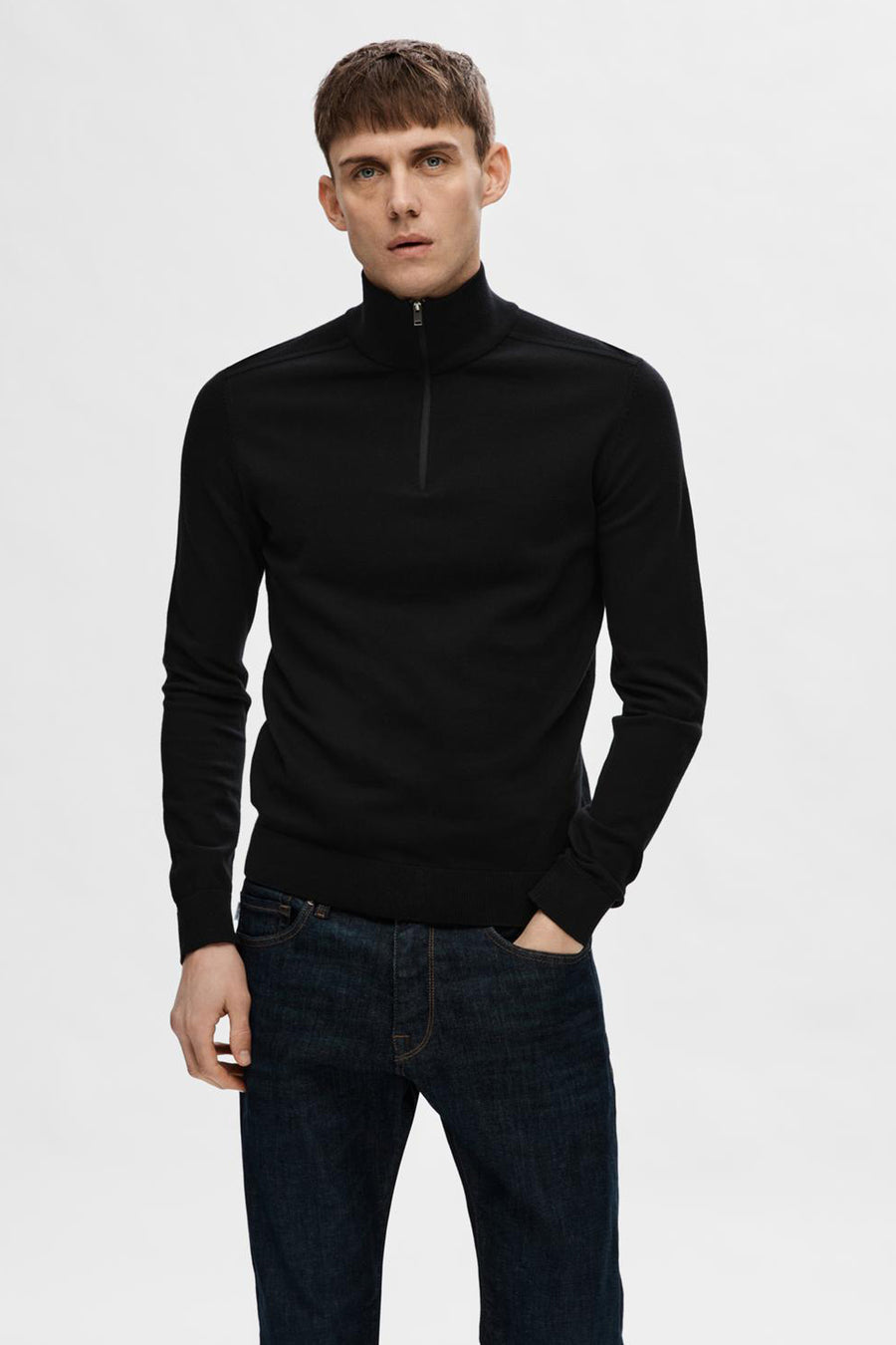 Pull noir de SELECTED, porté avec un jean bleu foncé, avec fermeture éclair au col.